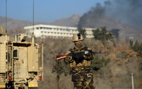 An Afghan security personnel stands guard as smoke billows from the Intercontinental Hotel during a fight between gunmen and Afghan security forces in Kabul on January 21, 2018.