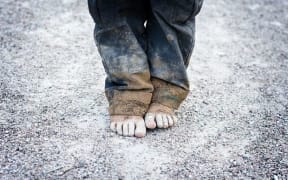 A child's bare feet on a gravel road