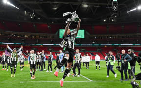 Newcastle United's Brazilian midfielder Joelinton celebrates with the League Cup trophy after winning the English League Cup final against Liverpool, 2025.
