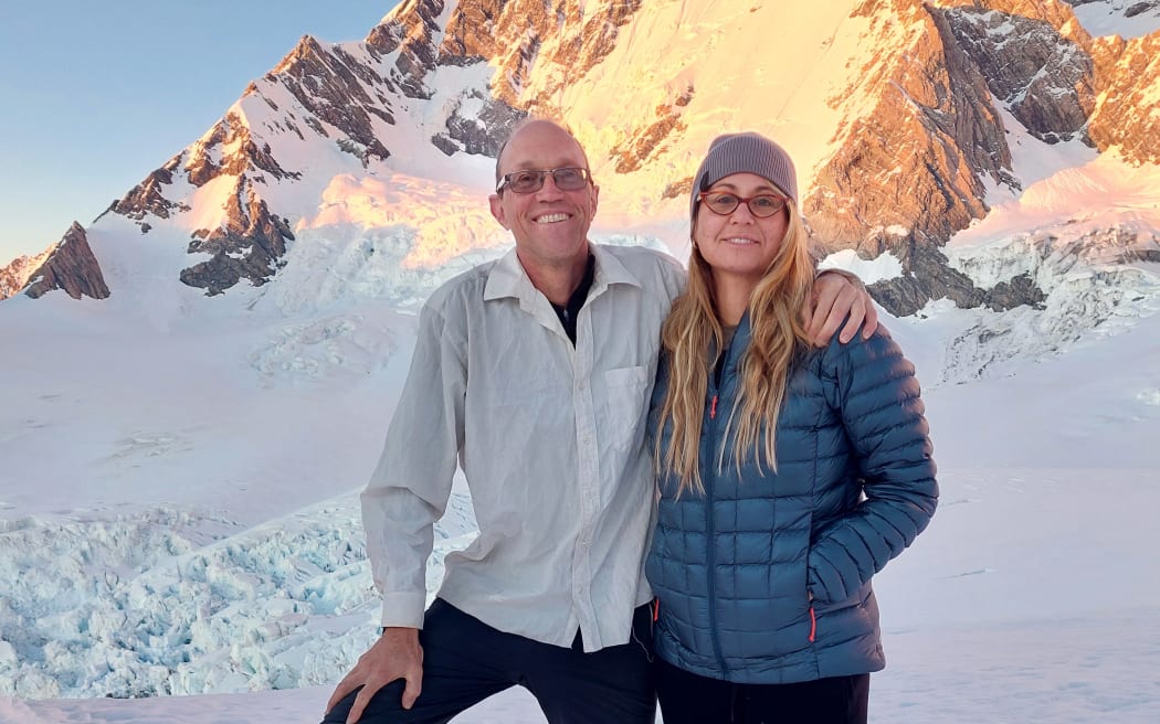 Chris and Toni smile at the camera. They stand on a snowy mountainside.