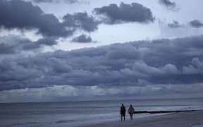 TREASURE ISLAND, FLORIDA - SEPTEMBER 27: People walk the beach at sunset in advance of the arrival of Hurricane Ian on September 27, 2022 in Treasure Island, Florida. Ian is expected in the Tampa Bay area Wednesday night into early Thursday morning.   Win McNamee/Getty Images/AFP (Photo by WIN MCNAMEE / GETTY IMAGES NORTH AMERICA / Getty Images via AFP)