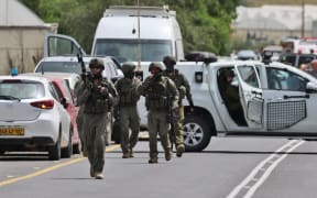 Israeli forces and emergency personnel gather near the Hamra junction, in the northern part of the Jordan valley in the occupied West Bank, following a shooting attack on April 7, 2023. - Two women were killed and another seriously wounded in a shooting attack on a vehicle in the occupied West Bank, Israeli army and medics said on April 7. (Photo by Jaafar ASHTIYEH / AFP)