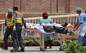 Pakistani rescue workers and paramedics with a burns victim injured after the oil tanker fire.