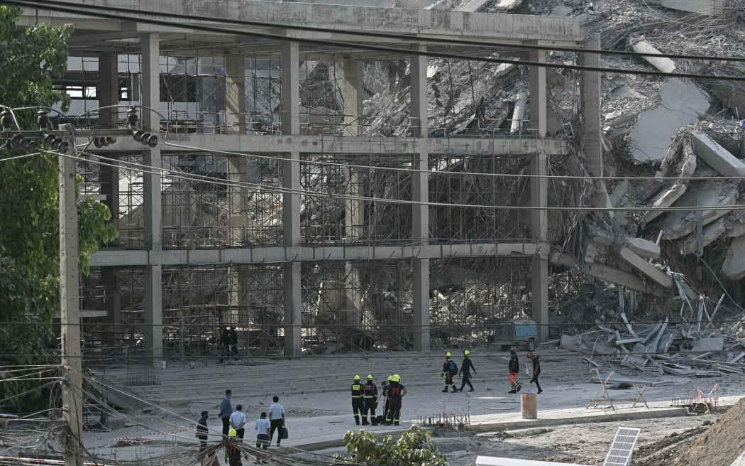 Rescue workers look at the debris of a construction site after a building collapsed in Bangkok on March 28, 2025, following an earthquake. A powerful earthquake rocked central Myanmar on March 28, buckling roads in capital Naypyidaw, damaging buildings and forcing people to flee into the streets in neighbouring Thailand. (Photo by Lillian SUWANRUMPHA / AFP)