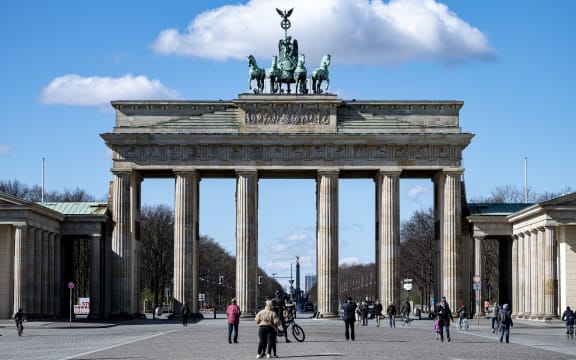 Passers-by stand on Pariser Platz in front of the Brandenburg Gate, 20 March.