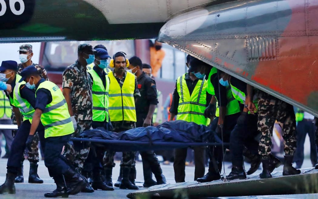 Nepalese soliders carry the body of a victim killed in a Tara Air plane crash as it arrives in Kathmandu, Nepal, 30 May, 2022.