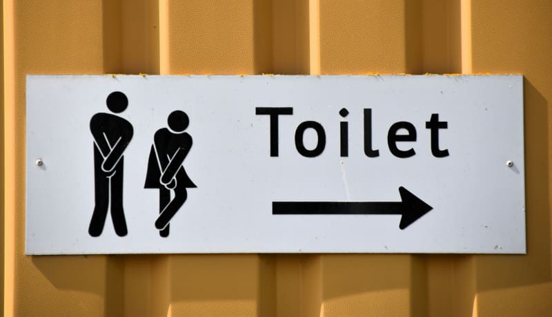 Toilet sign with two figures desperate to go.