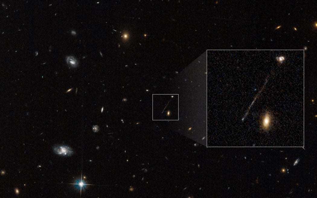 This Hubble Space Telescope archival photo captures a curious linear feature that is so unusual it was first dismissed as an imaging artifact from Hubble's cameras. But follow-up spectroscopic observations reveal it is a 200,000-light-year-long chain of young blue stars. A supermassive black hole lies at the tip of the bridge at lower left. The black hole was ejected from the galaxy at upper right. It compressed gas in its wake to leave a long trail of young blue stars. Nothing like this has ever been seen before in the universe. This unusual event happened when the universe was approximately half its current age.