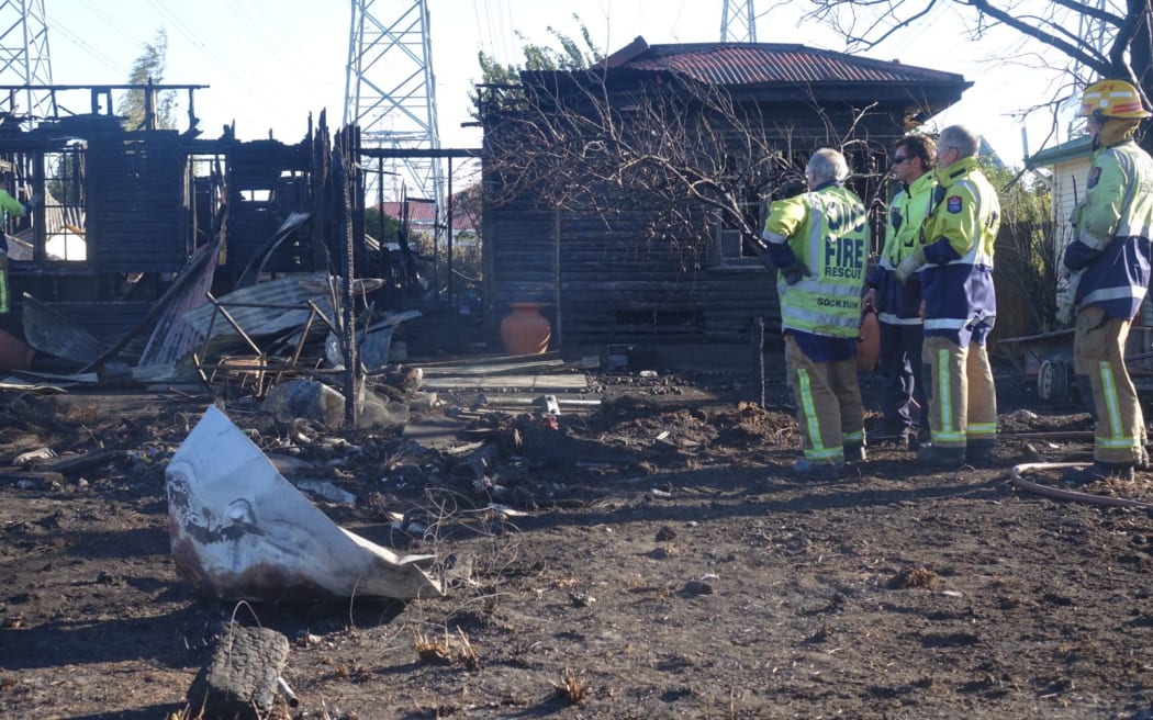 Firefighters survey a destroyed house.