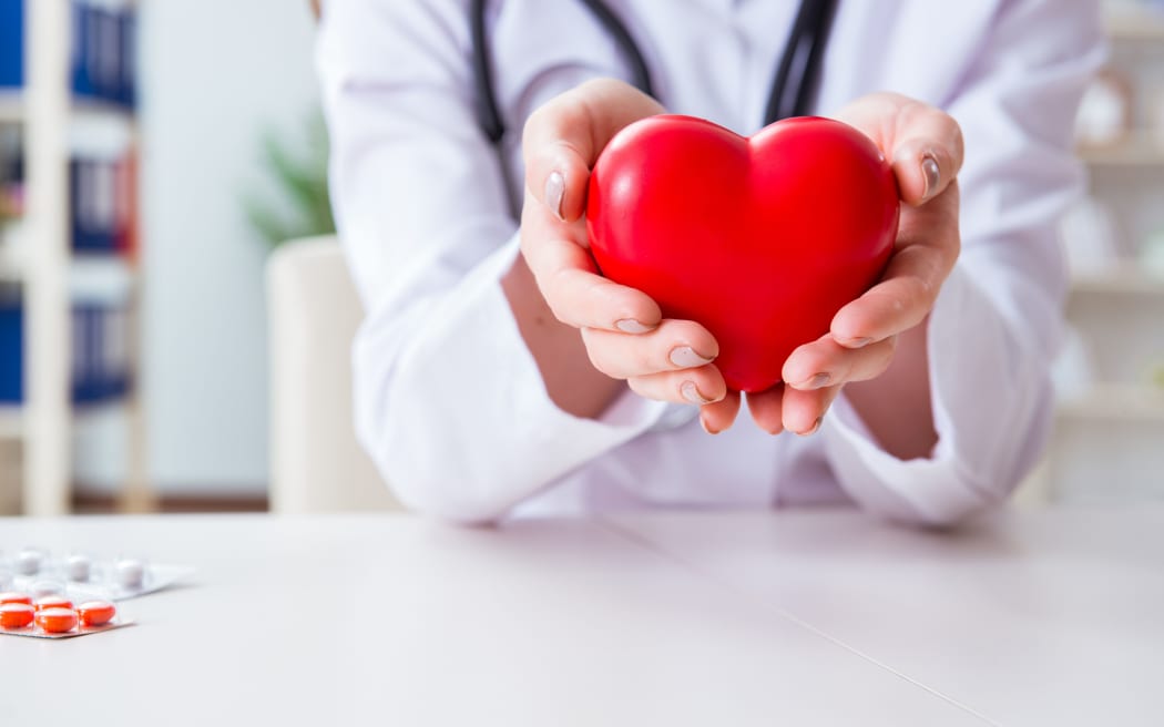 Doctor cardiologist with red heart in the hospital