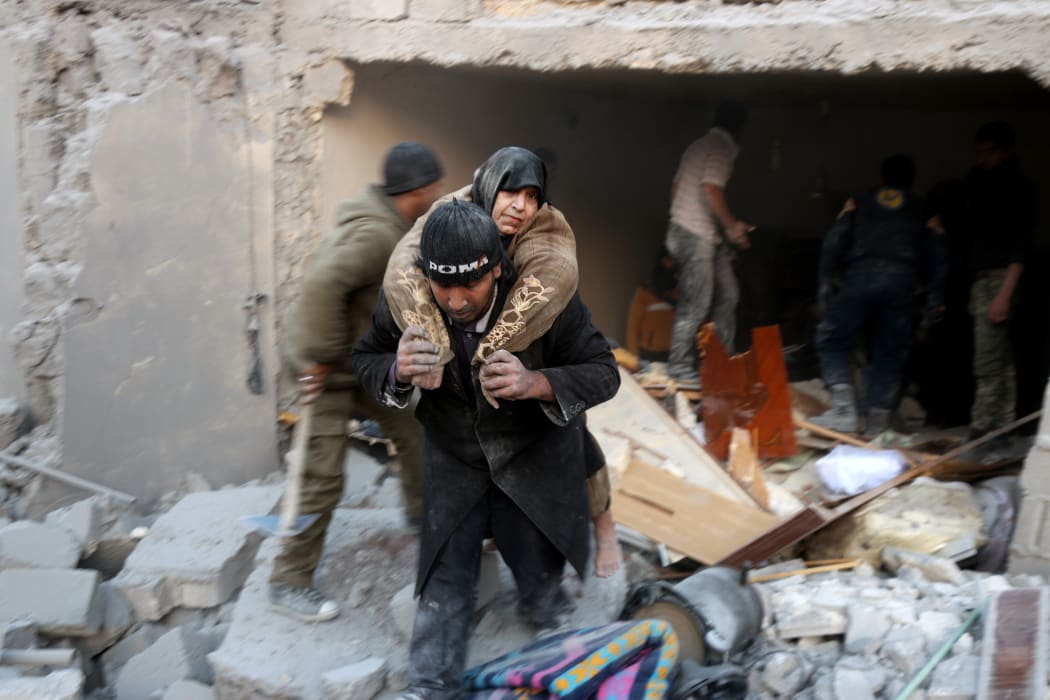 A rescuer carries a woman from the rubble of a building in Aleppo's rebel-held district of al-Hamra on 20 November.