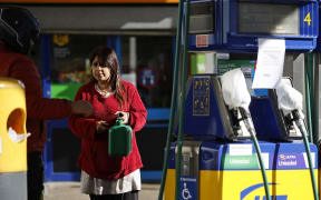 A woman holds a petrol can as a motorcyclist speaks to her at partly taped-off petrol and diesel pumps at a petrol station in Leyton, east London on September 29, 2021.