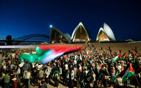 Protesters show their support for Palestinians during a rally in front of the Opera House in Sydney on October 9, 2023. Israel relentlessly pounded the Gaza Strip overnight and into October 9 as fighting with Hamas continued around the Gaza Strip, as the death toll from the war against the Palestinian militants surged above 1,100. (Photo by Izhar KHAN / AFP)
