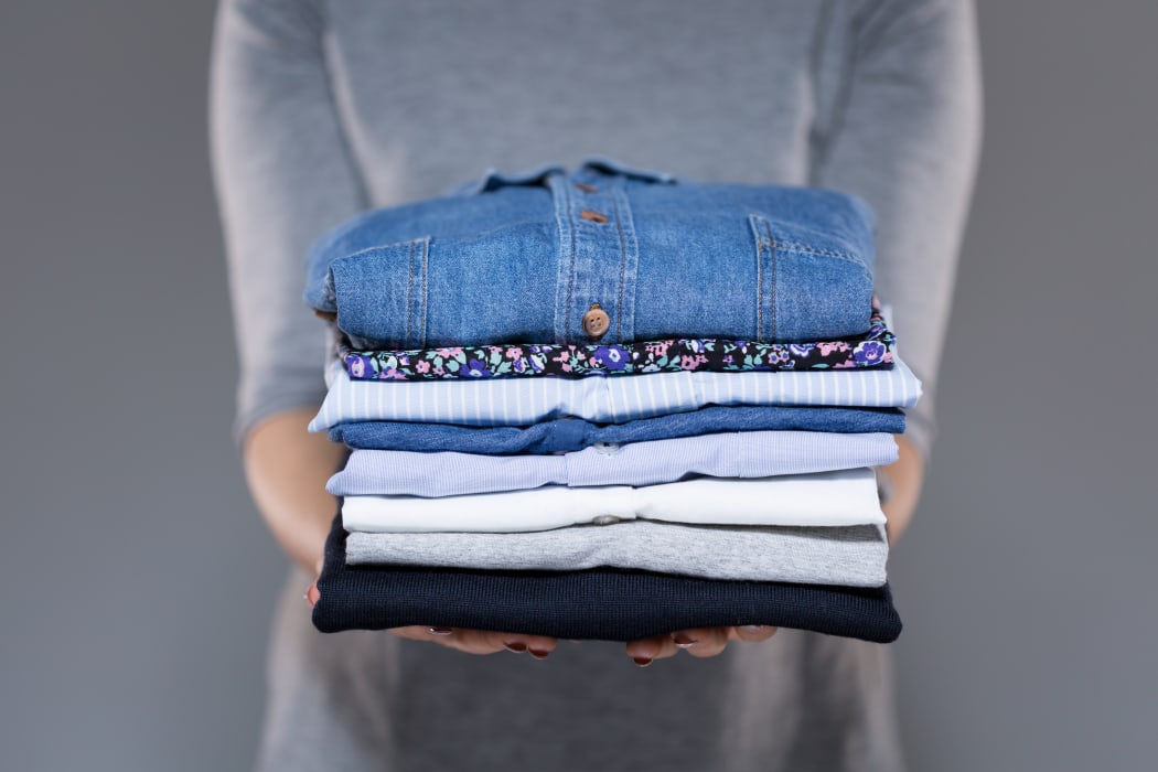 Woman holding folded clothes in hands