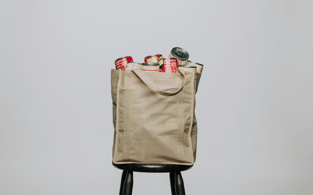A bag of tinned food in a bag on a chair.