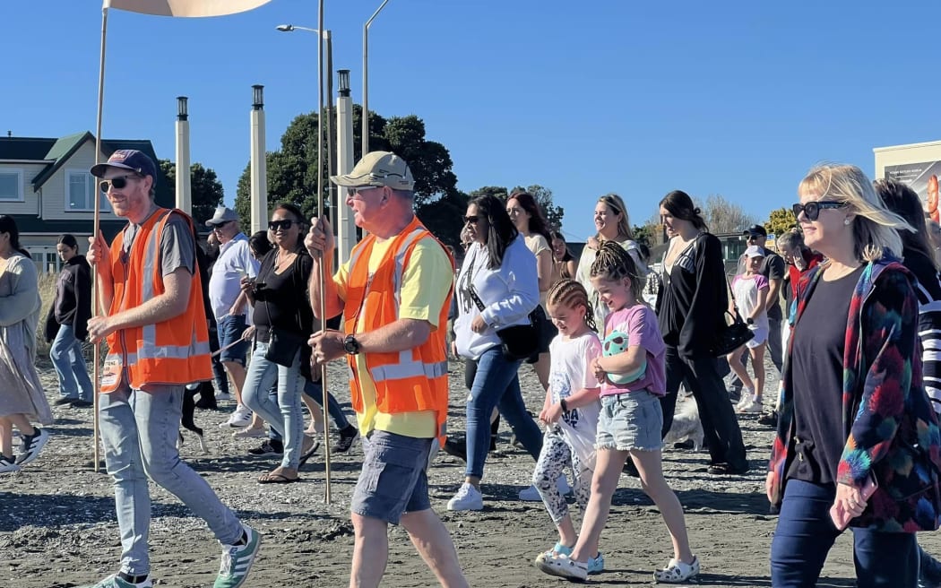 People protesting plans to demolish Petone Wharf walk along Petone Beach 28 April 2024.
