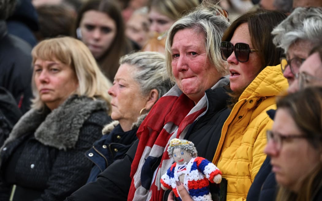 Members of the public cry as they gather along the Procession Route in London on September 19, 2022, during the State Funeral Service of Queen Elizabeth II.
