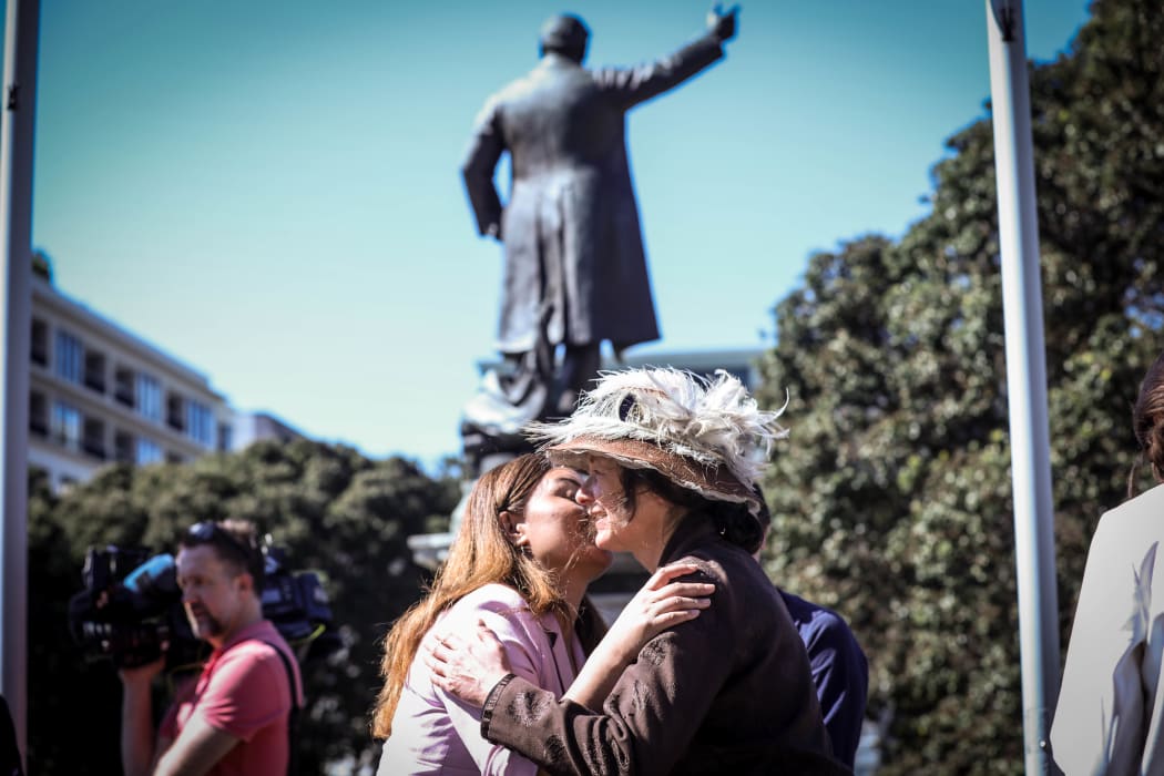 Green Party co-leader Marama Davidson greets a Suffrage Day petition re-enacter in front of a statue of Premier Richard Seddon who opposed women's suffrage
