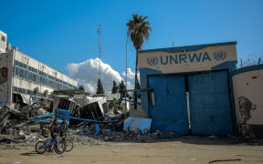 (FILES) People walk past the damaged Gaza City headquarters of the United Nations Relief and Works Agency for Palestine Refugees (UNRWA) on February 15, 2024, amid ongoing battles between Israel and the militant group Hamas. - Israel faced a mounting international backlash on October 29 after its parliament approved a bill banning the main UN aid agency for the devastated Gaza Strip. Despite objections from the United States and warnings from the UN Security Council, Israeli lawmakers overwhelmingly passed the bill banning the United Nations agency for Palestinian refugees, UNRWA, from working in Israel and annexed east Jerusalem. (Photo by AFP)