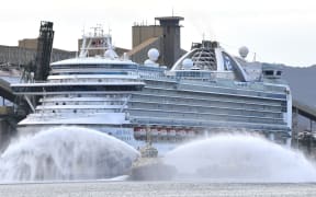 A tug boat gives a water salute as cruise liner Ruby Princess prepares to leave Port Kembla, some 80 kilometres south of Sydney on April 23, 2020.