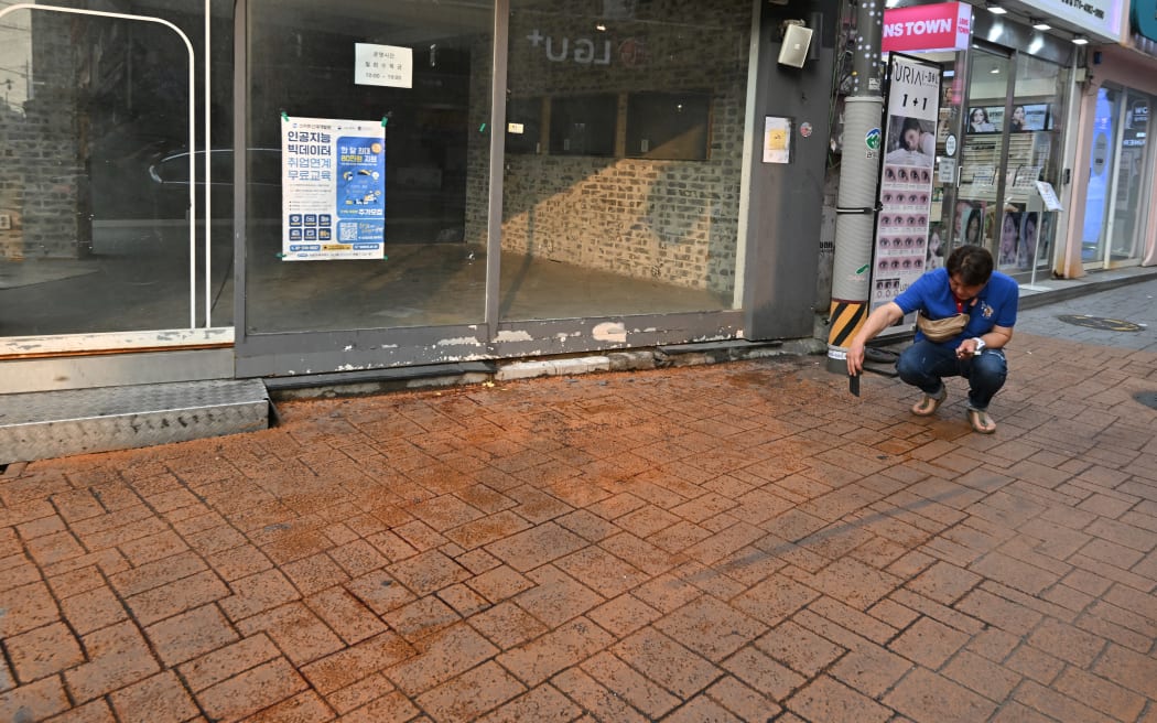 A man takes pictures at the scene of an attack near the Sillim subway station in southwest Seoul on July 21, 2023. One person was killed and three more wounded when a man went on a "stabbing rampage" near a subway station in the South Korean capital Seoul on July 21, police told AFP. (Photo by Jung Yeon-je / AFP)