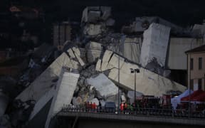 Rescuers inspect the rubble and wreckages by the Morandi motorway bridge after a section collapsed earlier in Genoa.