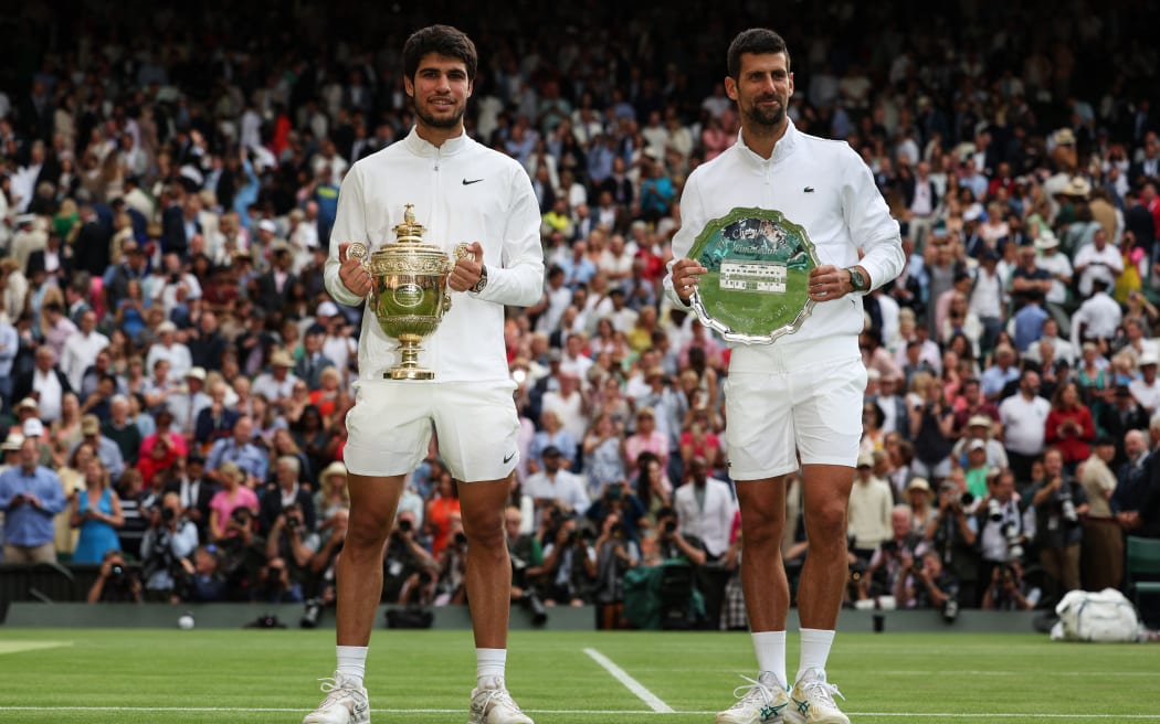Spain's Carlos Alcaraz (L) holds the winner's trophy as he poses with Serbia's Novak Djokovic after their men's singles final tennis match on the last day of the 2023 Wimbledon Championships at The All England Tennis Club in Wimbledon, southwest London, on July 16, 2023. (Photo by Adrian DENNIS / AFP) / RESTRICTED TO EDITORIAL USE