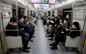 People wearing face masks amid concerns over the spread of the Covid-19 coronavirus, commute on a train in Tokyo on 6 April 2020.