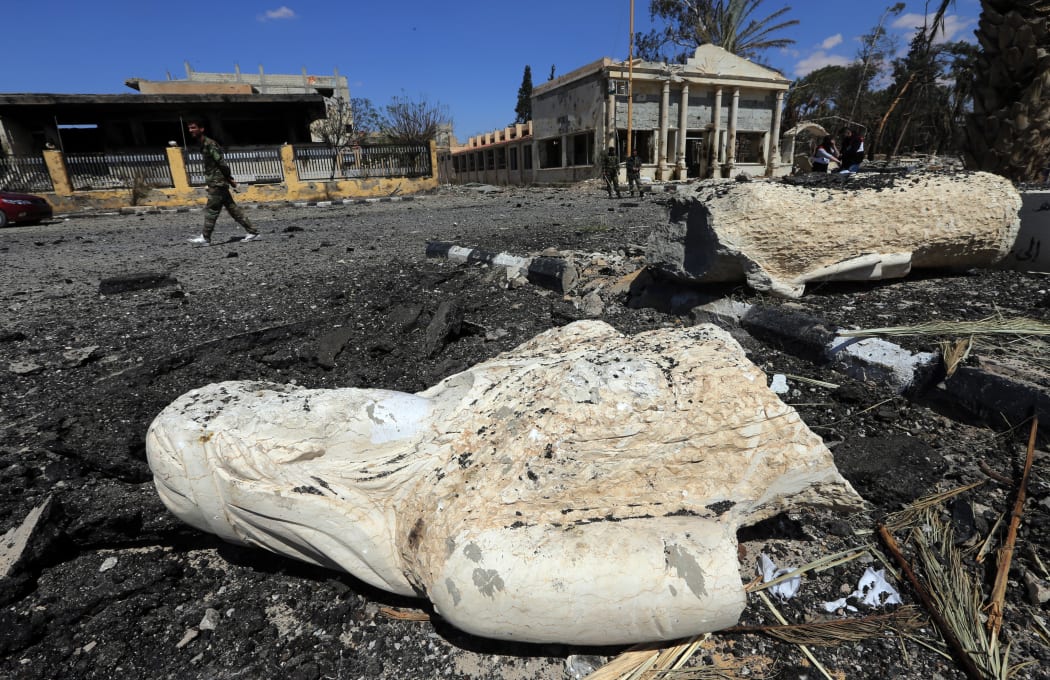 A Syrian soldier walks past the remains of a statue in a heavily damaged street in the ancient Syrian city of Palmyra on 31 March.