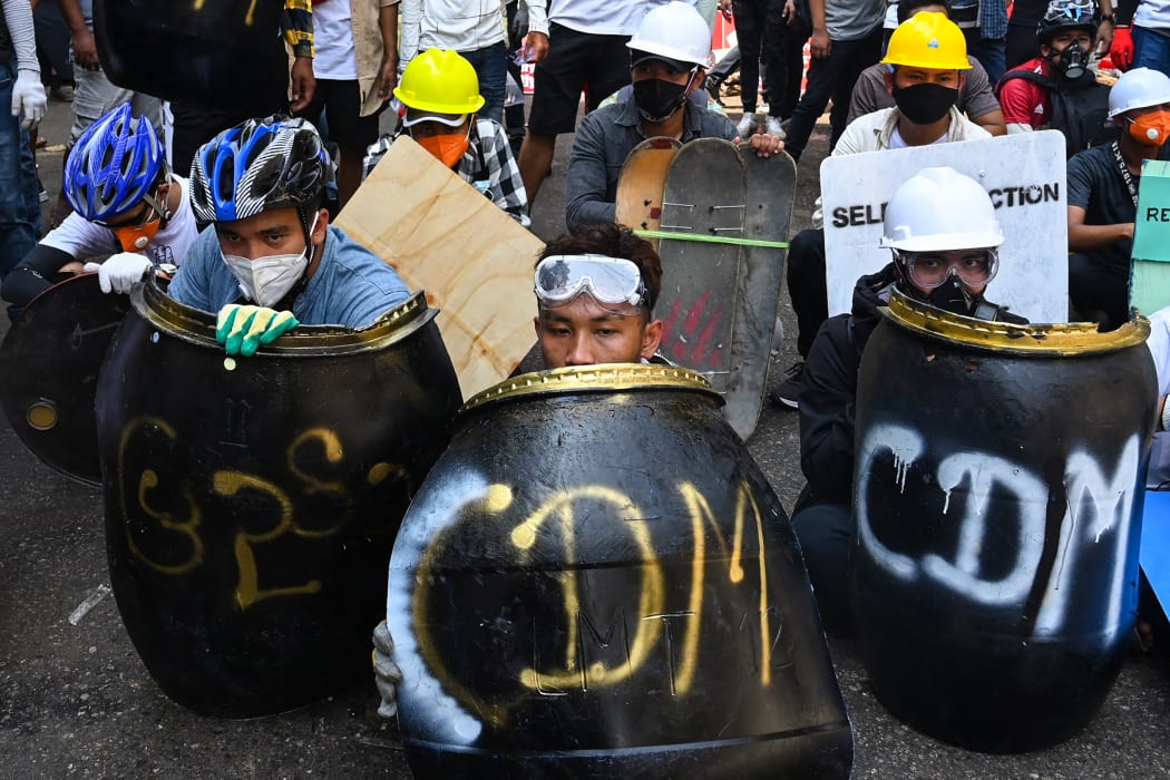 Protesters take cover behind homemade shields during a demonstration against the military coup in Yangon on February 28, 2021.