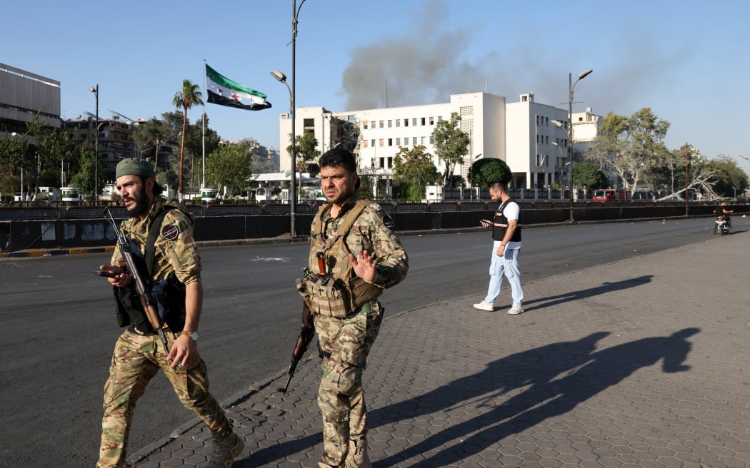 Syrian security forces stand guard in front of the heavily damaged Syrian army and defence ministry headquarters complex in Damascus, following Israeli strikes on July 16, 2025. (Photo by Bakr ALkasem / AFP)