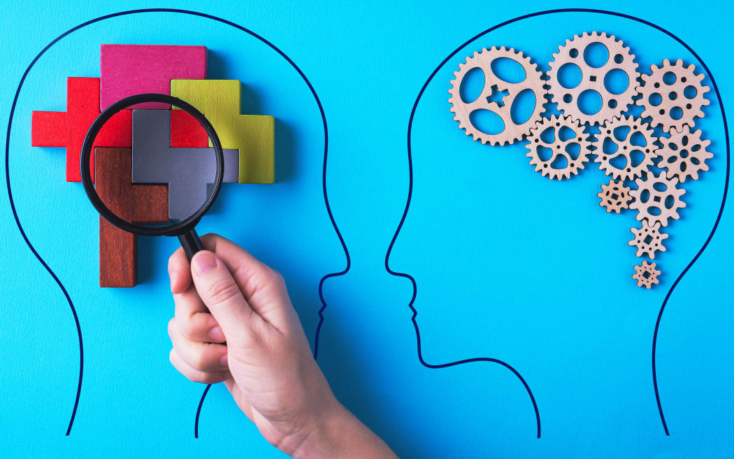 Human brain is made gear mechanism and colourful shapes on blue background. The brain is viewed through a magnifying glass. Two different thought processes, concept of different thinking.