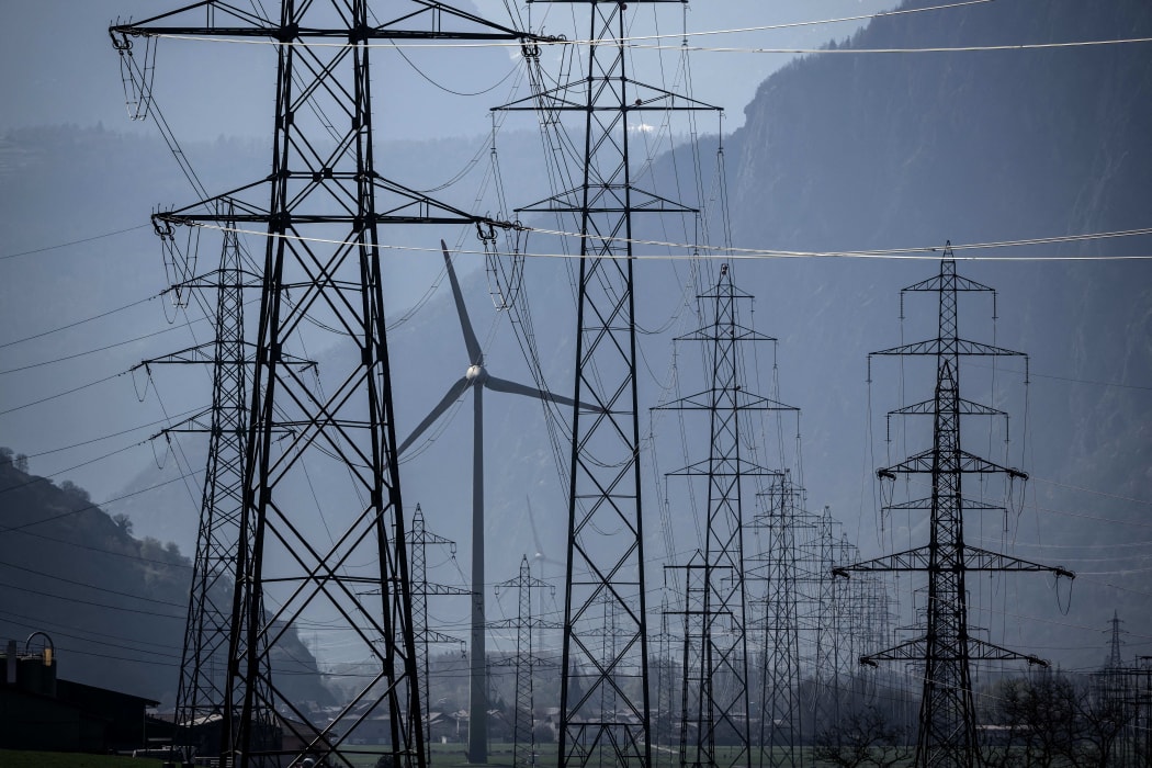A wind turbine is surrounded by electricity pylons near Evionnaz, Canton of Valais, western Switzerand on March 28, 2022. - (Photo by Fabrice COFFRINI / AFP)
