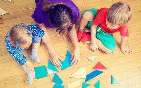 teacher and kids playing with geometric shapes, early learning