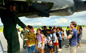 A group of schoolchildren boarding a military aircraft to be repatriated to New Caledonia after the Vanuatu earthquake.