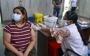 A health worker inoculates a woman with a dose of the Covishield Covid-19 coronavirus vaccine at a vaccination centre in New Delhi on May 13, 2021.