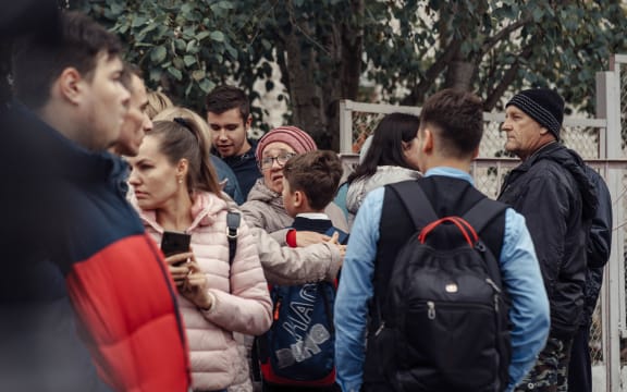 A woman hugs a boy surrounded by other people near the scene of a school shooting in Izhevsk on 26 September, 2022.