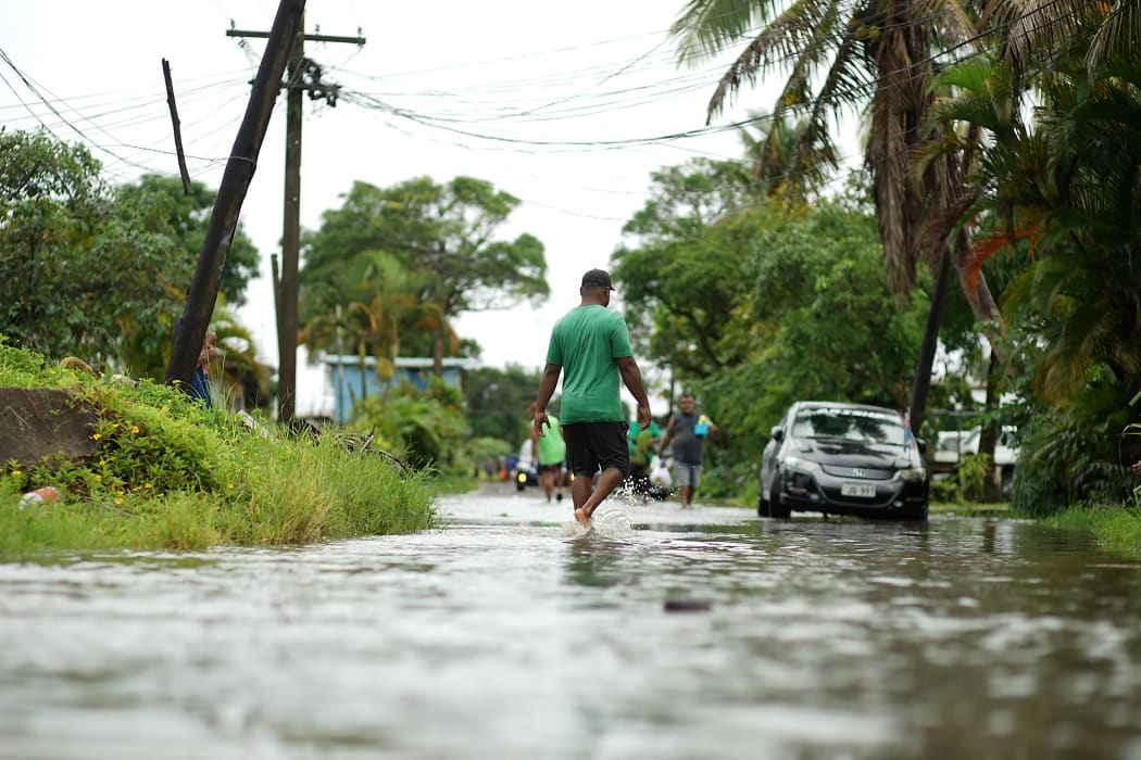 Residents wade through the flooded streets in Fiji's capital city of Suva on December 16, 2020, ahead of super Cyclone Yasa.