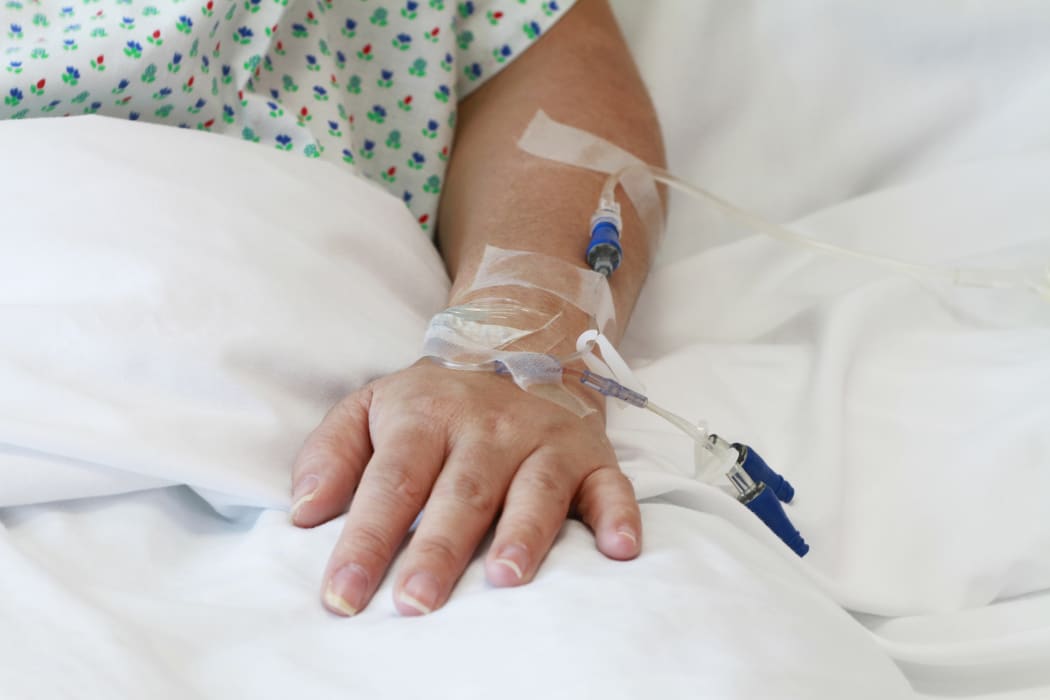 A file photo of a patient in a hospital bed with an IV drip in the arm