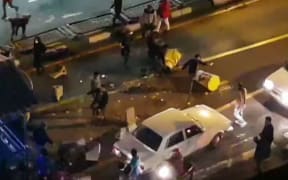 An image grab taken from a handout video released by Iran's Mehr News agency reportedly shows a group of men pushing traffic barriers in a street in Tehran on December 30, 2017.