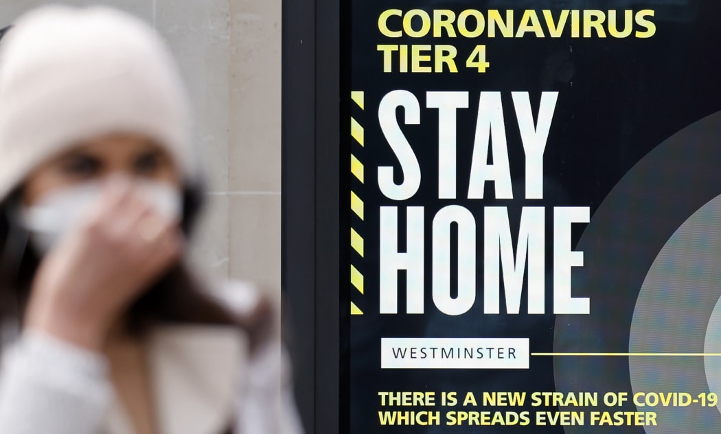 A pedestrian wearing a mask walks past a sign alerting people that Covid-19 cases are very high in London on December 23, 2020.