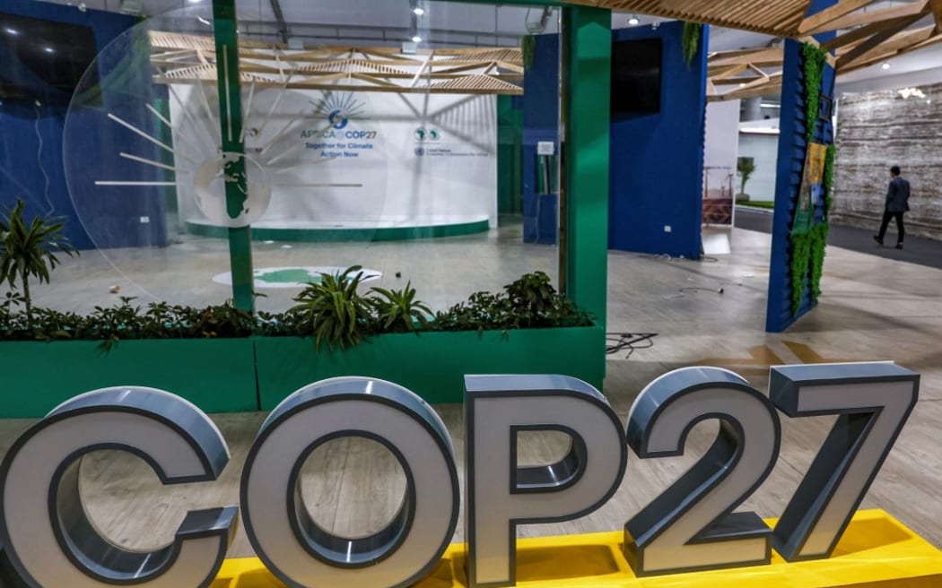 A person walks near the COP27 climate conference at the deserted hall at the Sharm el-Sheikh International Convention Centre, in Egypt's Red Sea resort city of the same name near the end of the climate conference on November 19, 2022. (Photo by AHMAD GHARABLI / AFP)