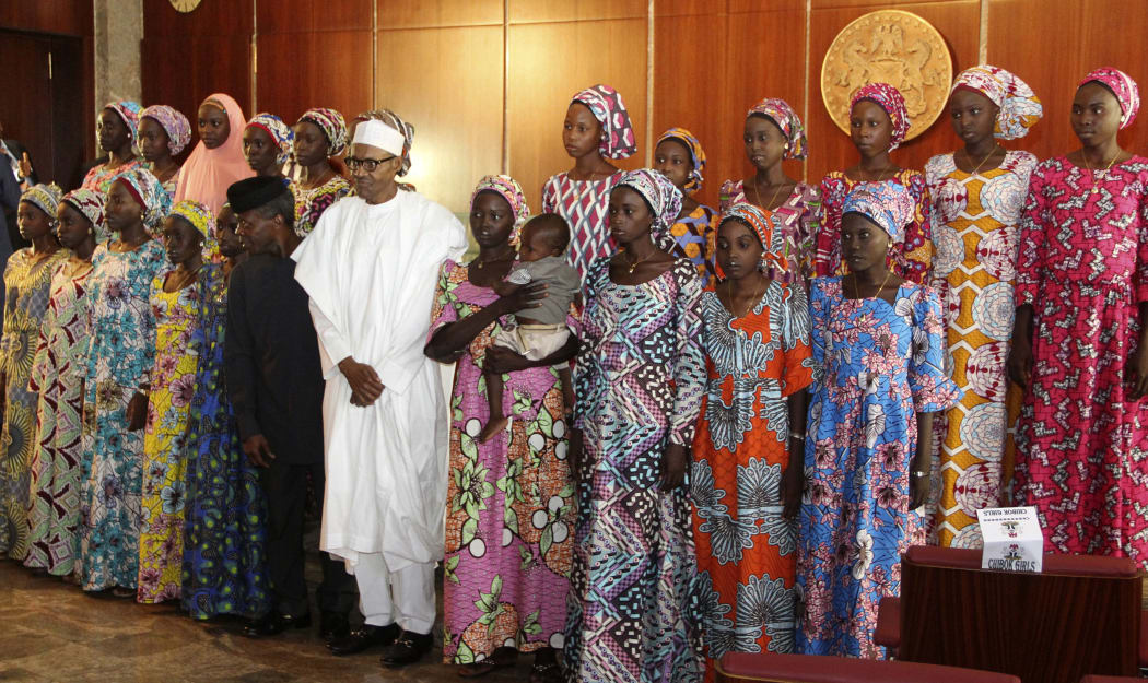 Nigerian President Muhammadu Buhari (C) with the 21 Chibok girls released by Boko Haram.
