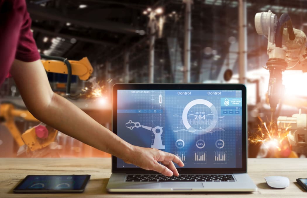 Engineer touching laptop check and control welding robotics automatic arms machine in intelligent factory automotive industrial with monitoring system software.