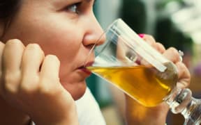 A woman drinks a glass of beer at a restaurant (file)