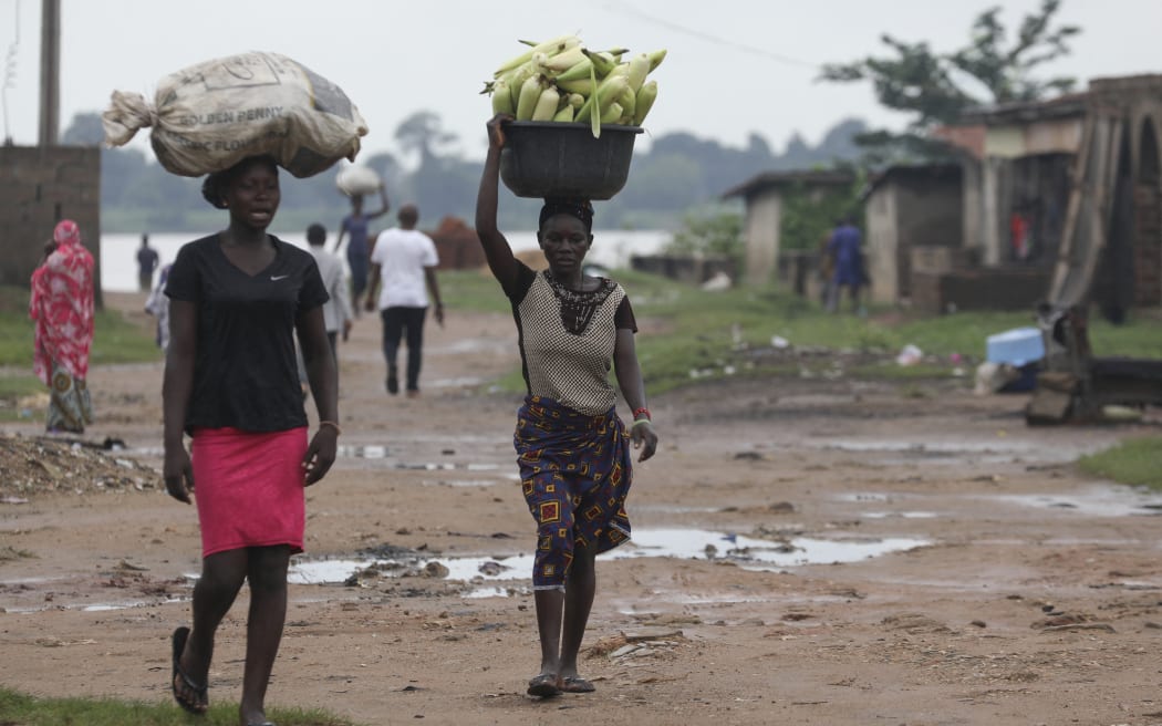 Women carry bags of maize at a farm in Northbank, Benue State, Nigeria on 12 August, 2021. Threatened by insecurity, farmers in Nigeria's farm belt are increasingly abandoning their land, leading to supply problems and adding to the already high cost of food in Africa's most populous country. Nigeria's Middle Belt and northwestern states have for years been caught in violence between normadic herdsman and farmers as climate change intensifies rivalries over water and land. But that violence has spiralled into security crisis tit-for-tat attacks and expanded into widespread kidnapping, cattle theft and criminal banditary.