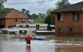 A resident fades through water in western Sydney on March 3, 2022, as the area faces its worst flooding after record rainfall caused its largest dam to overflow.