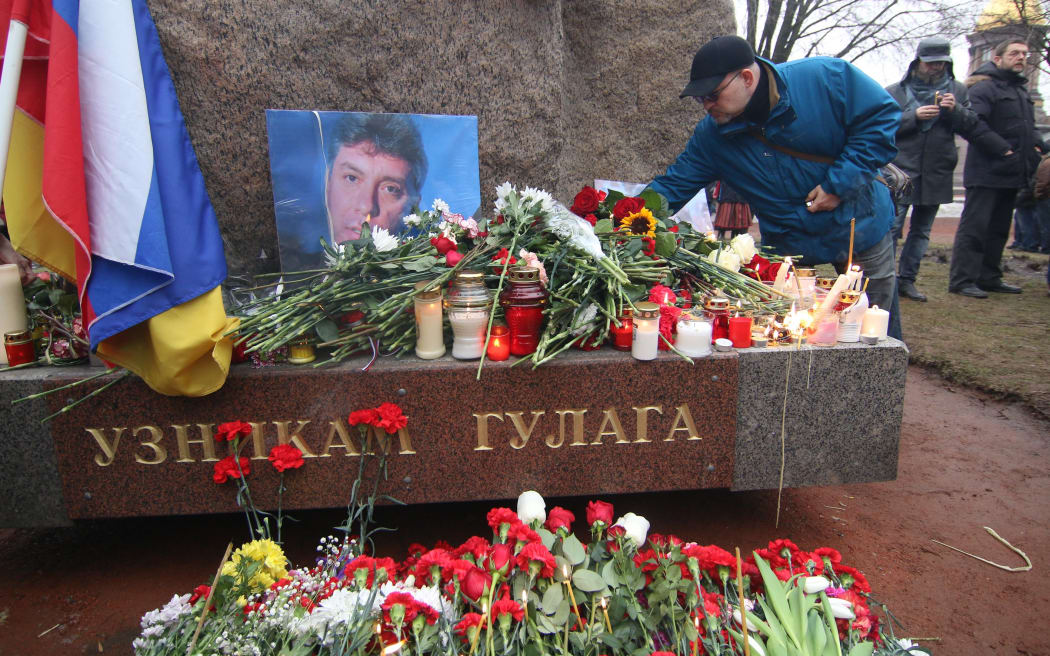 A man places flowers to the portrait of Boris Nemtsov during memorial ceremony on February 28, 2015 in Saint-Petesrburg, Russia. Russian opposition leader was shot dead in central Moscow late Friday in Moscow.