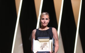 French director Julia Ducournau poses on stage with her trophy after she won the Palme d'Or for her film Titane at the Cannes Film Festival.