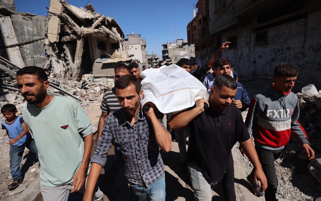 People carry the body of a Palestinian released by Israel under a Gaza ceasefire and hostage exchange, during his funeral in the Bureij refugee camp in the central Gaza Strip on October 18, 2025. Israel returned the bodies of 15 Palestinians to Gaza on October 18, bringing the total number handed over to 135, the health ministry in the Hamas-run territory said. (Photo by Eyad BABA / AFP)